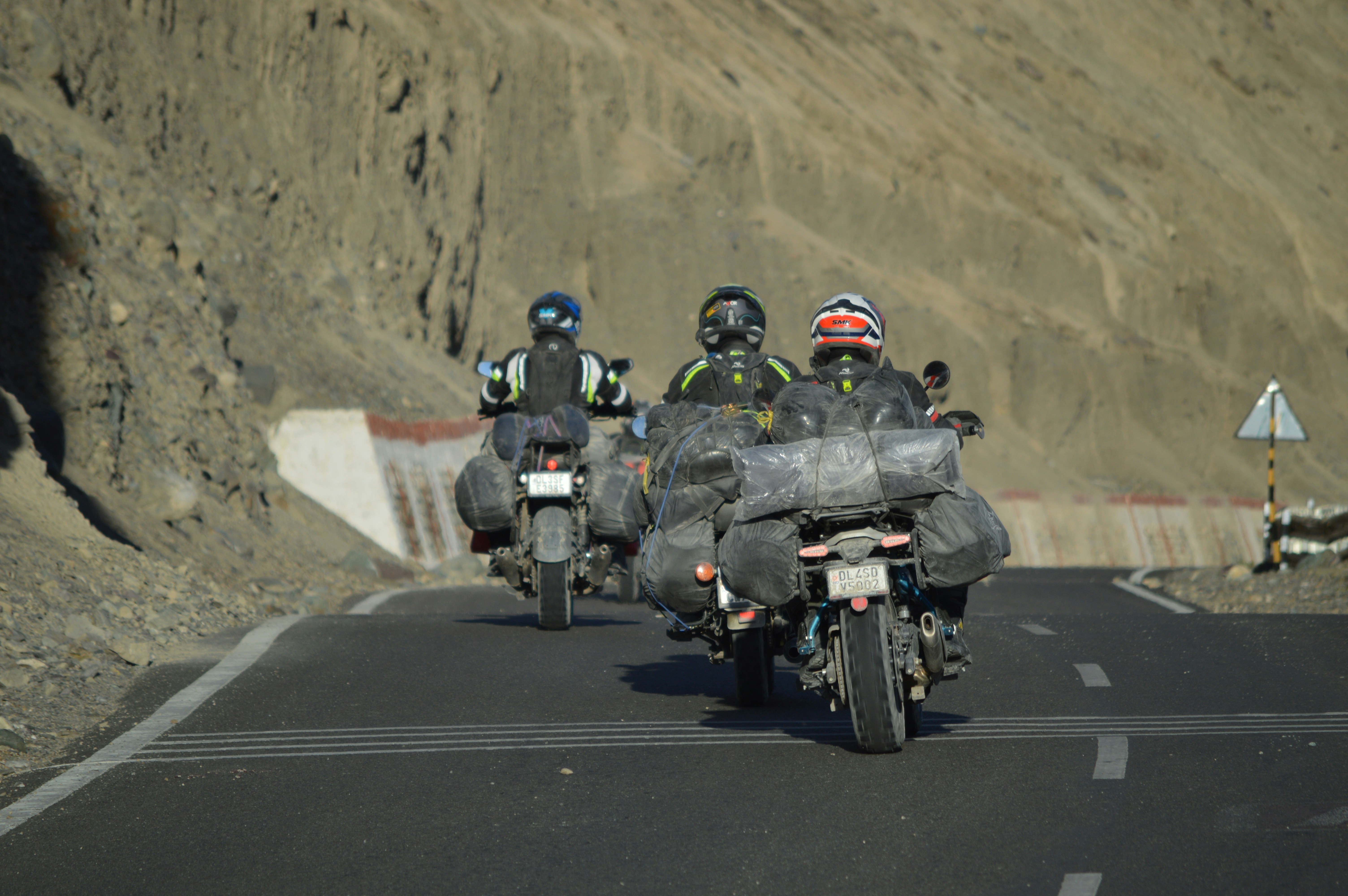 Three motorcyclists ride down a paved road.