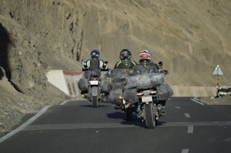 Three motorcyclists ride down a paved road.