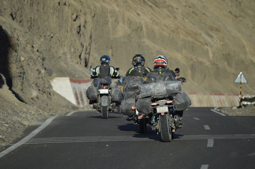 Three motorcyclists ride down a paved road.