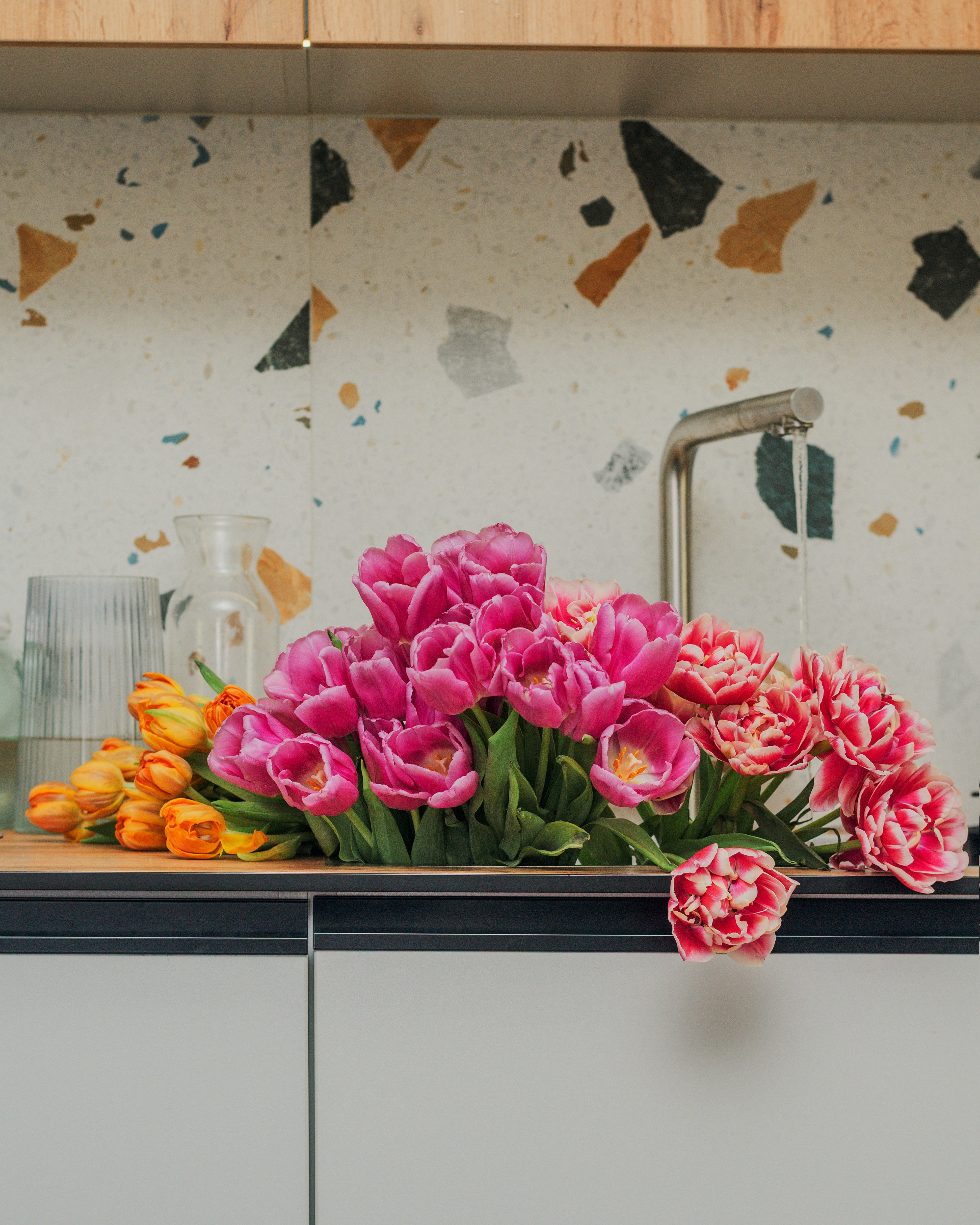 Pink and orange tulips arranged on a kitchen counter.