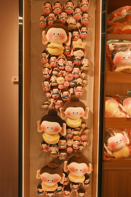 Vertical display of colorful custom plush toys arranged on a shelf, showing the variety produced by a Shenzhen plush manufacturing factory