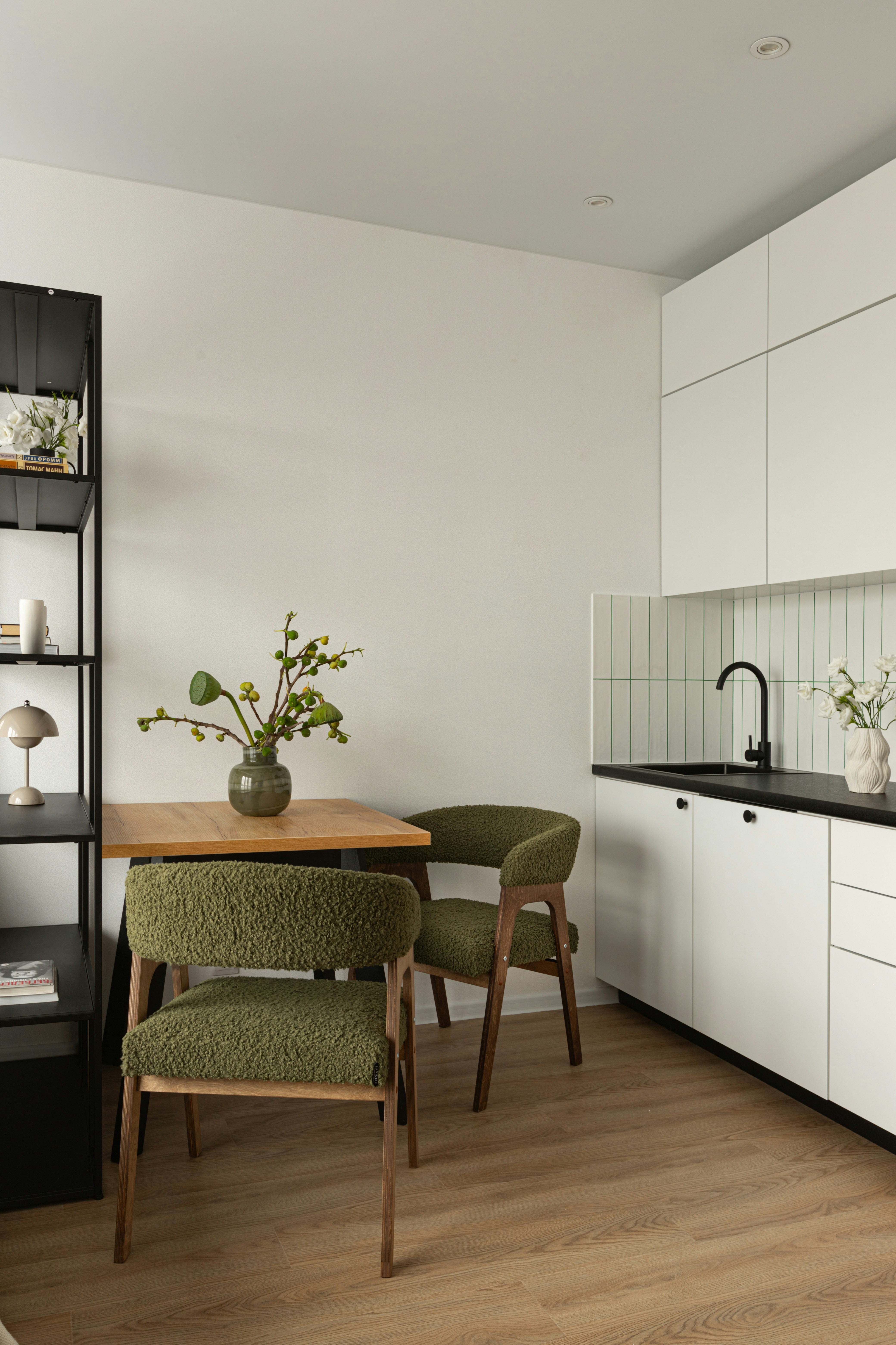 Modern kitchen with dining area and green chairs.