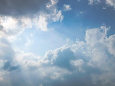 Sunlight breaking through dramatic clouds in a blue sky