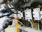 Electrician testing electrical panel with multimeter.