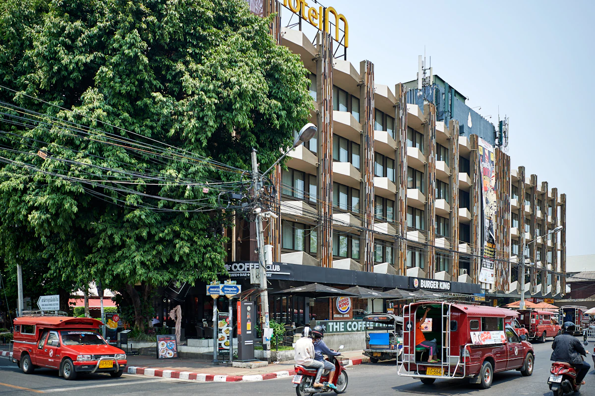 Red tuk-tuks passing a modern building in Bangkok, Thailand