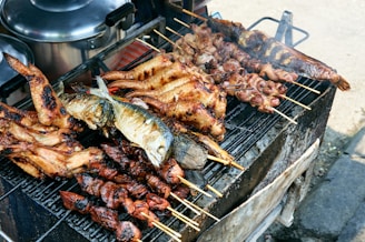 Various meats and fish grilling on a barbecue.