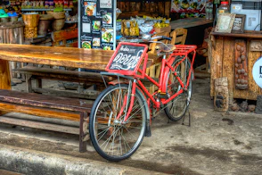 Red bicycle parked outside a wooden establishment.