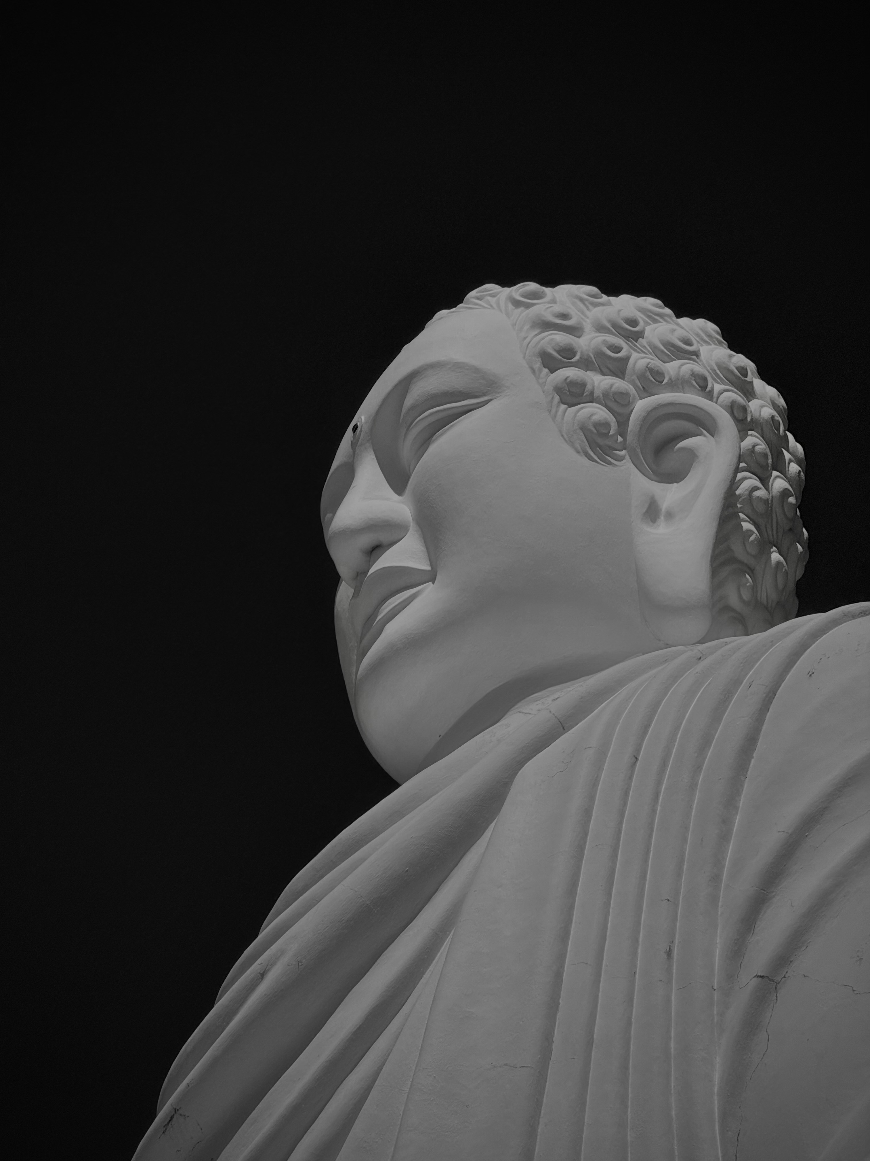 White buddha statue against a dark background.