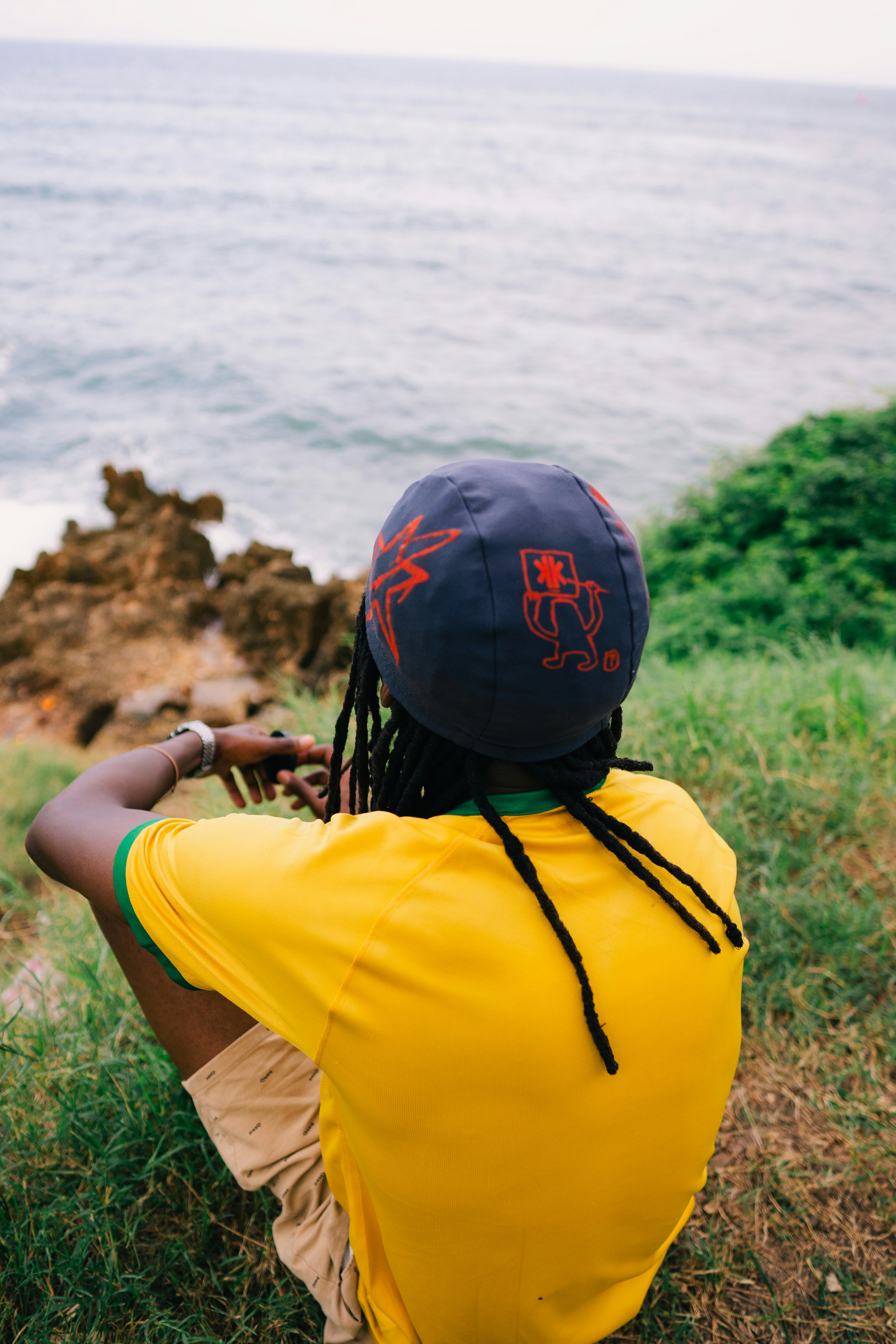Homem de camisa amarela olhando para o oceano