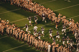 Football players run onto the field between cheering crowds