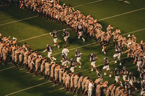 Football players run onto the field between cheering crowds