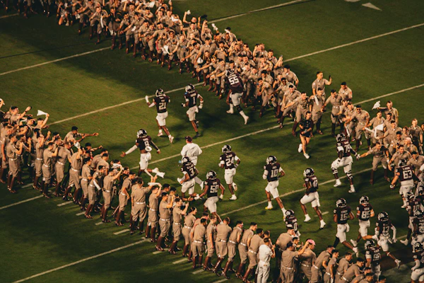 Football players running onto field between cheering crowds