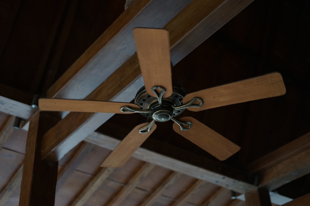 Ventilador de techo de madera de cinco aspas montado en un techo con vigas