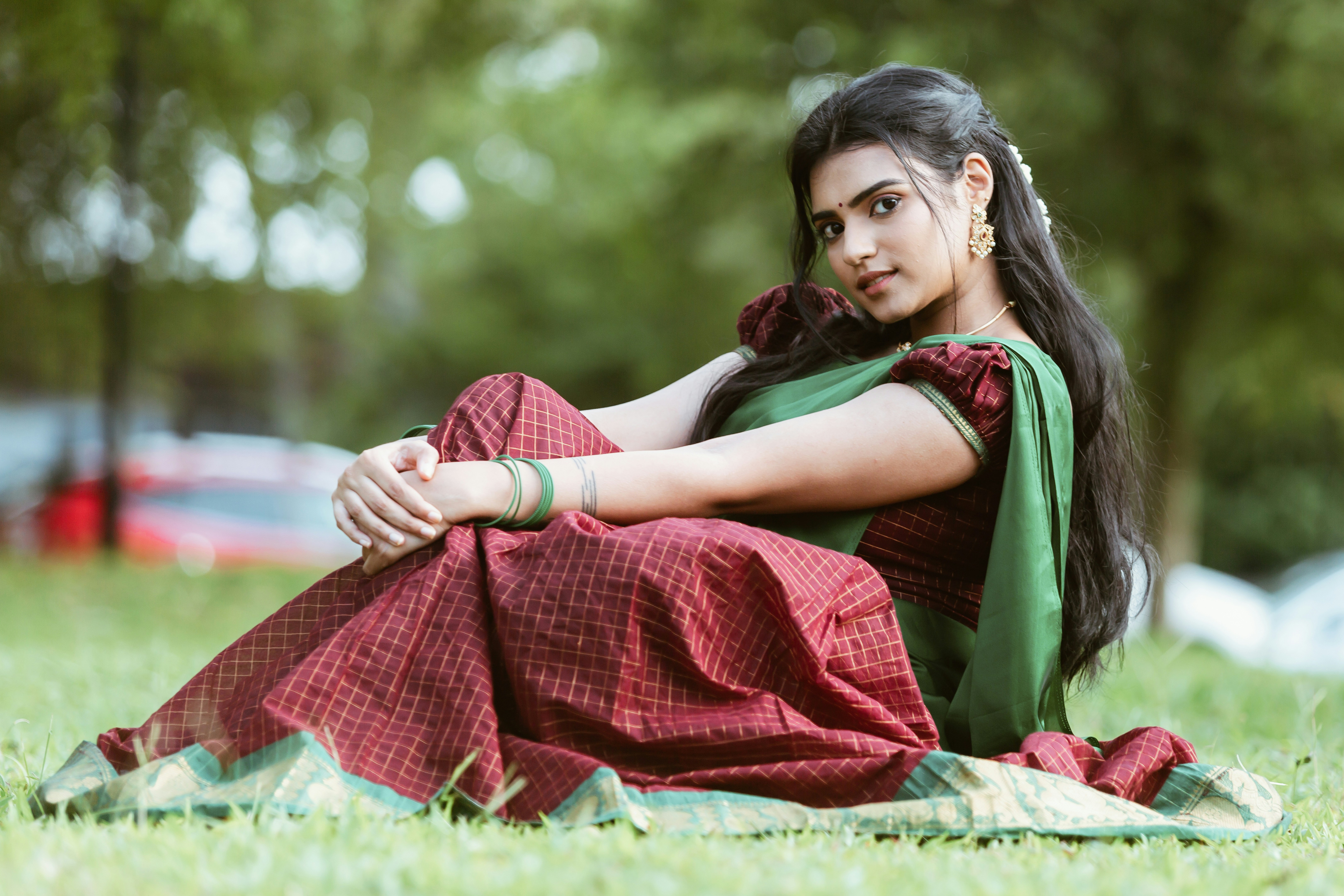Woman in traditional attire sits on grass