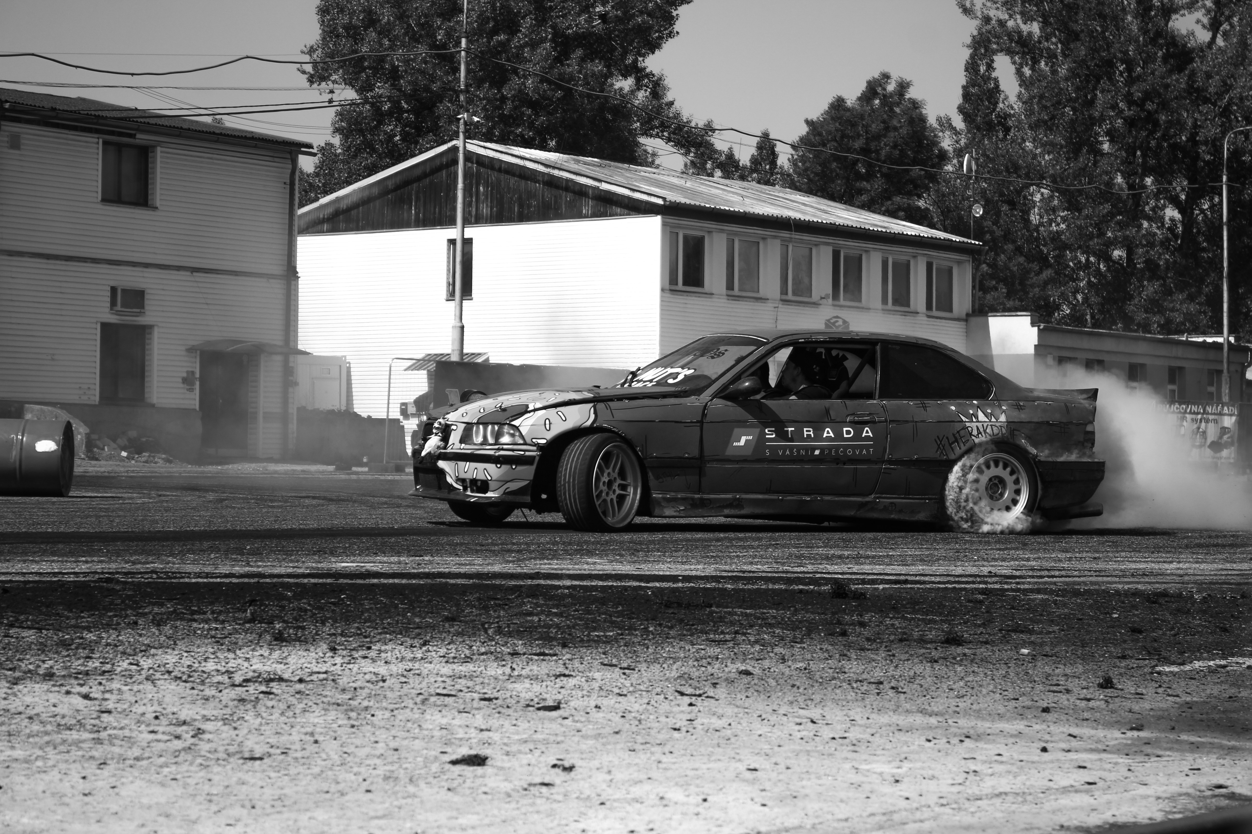 A car drifts, kicking up smoke on a street.
