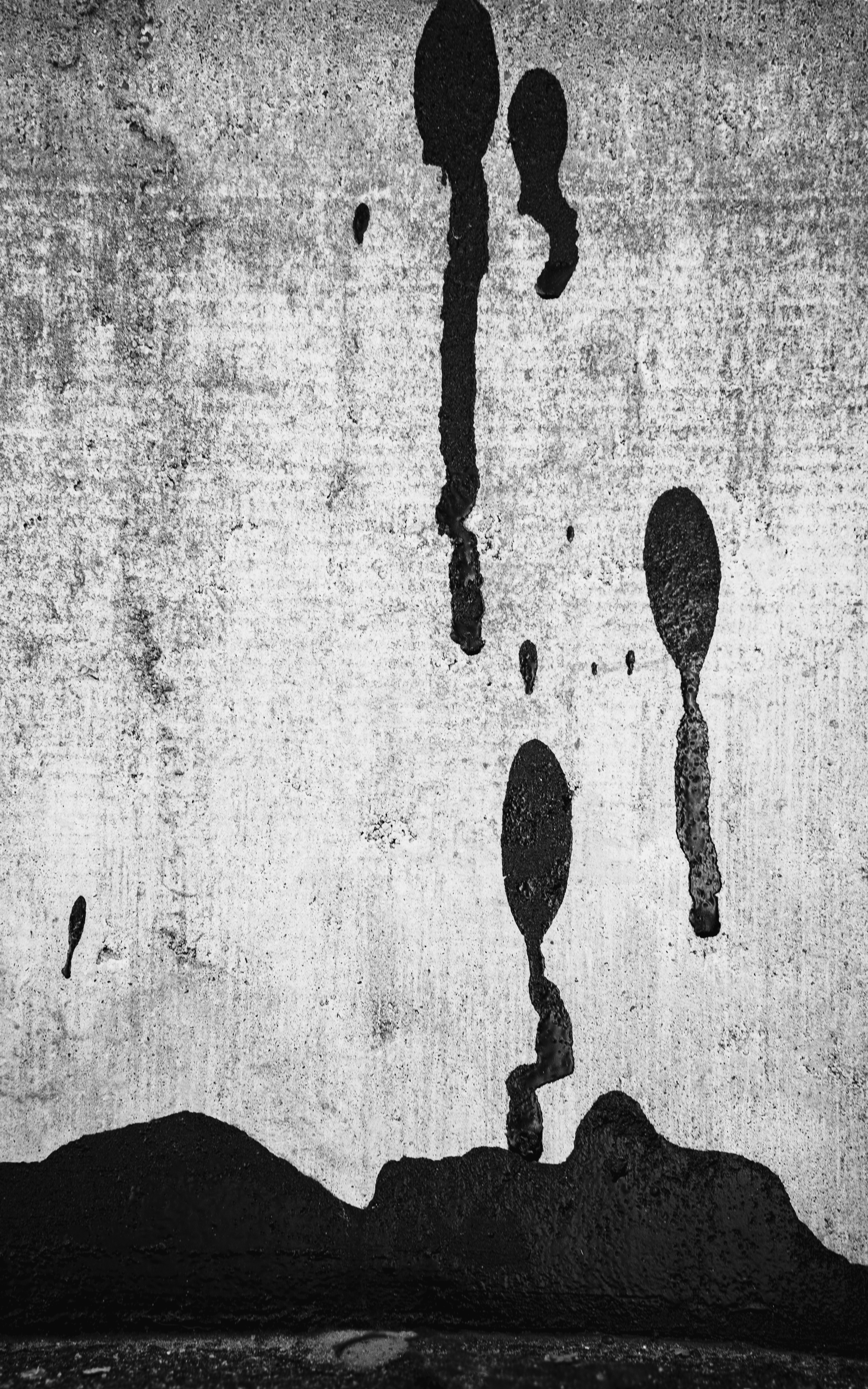 Black drips on a textured concrete wall