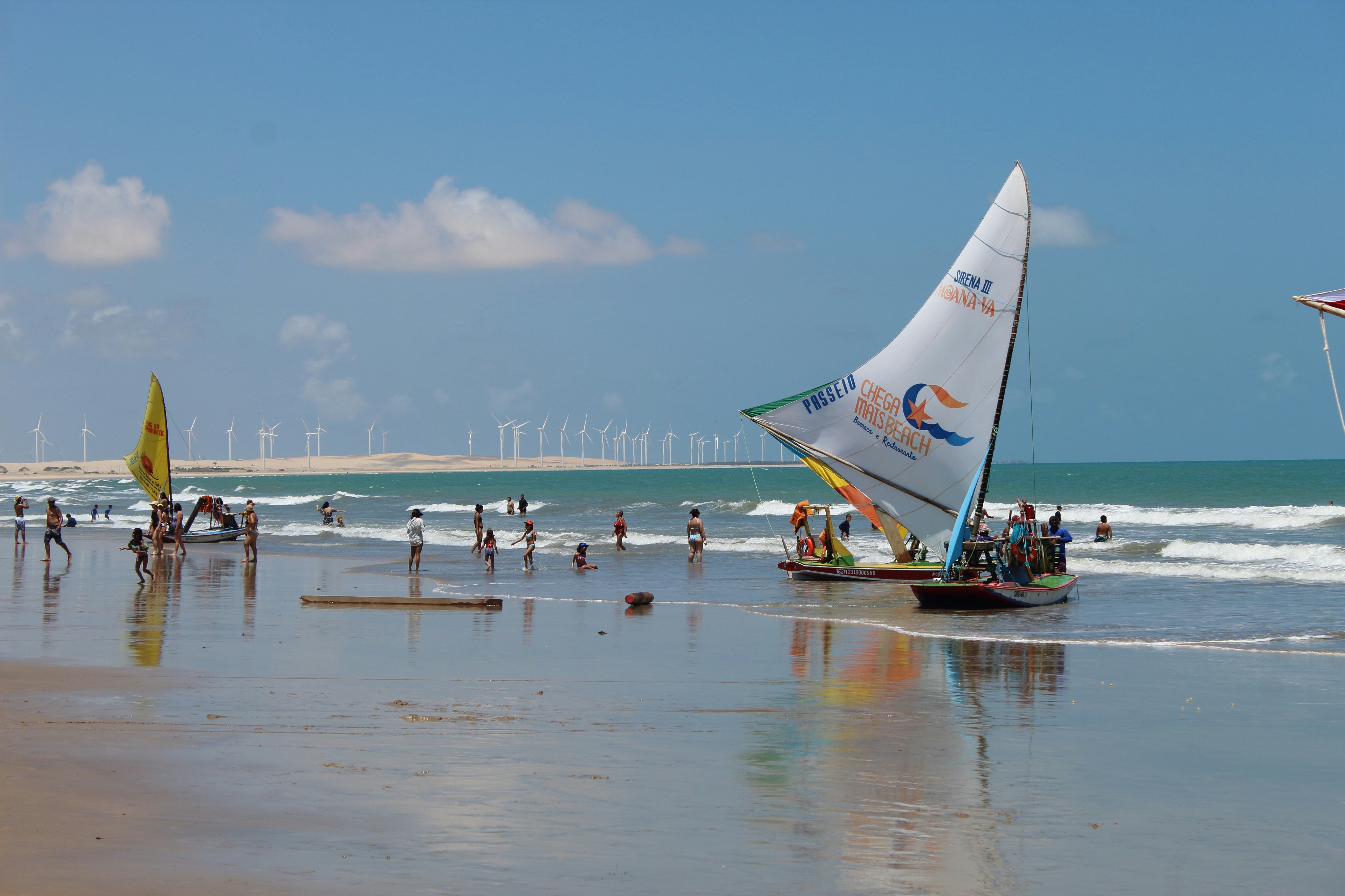 Sailboats on a beach with wind turbines in background