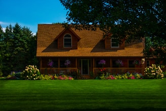 A wooden house with a porch and manicured lawn.