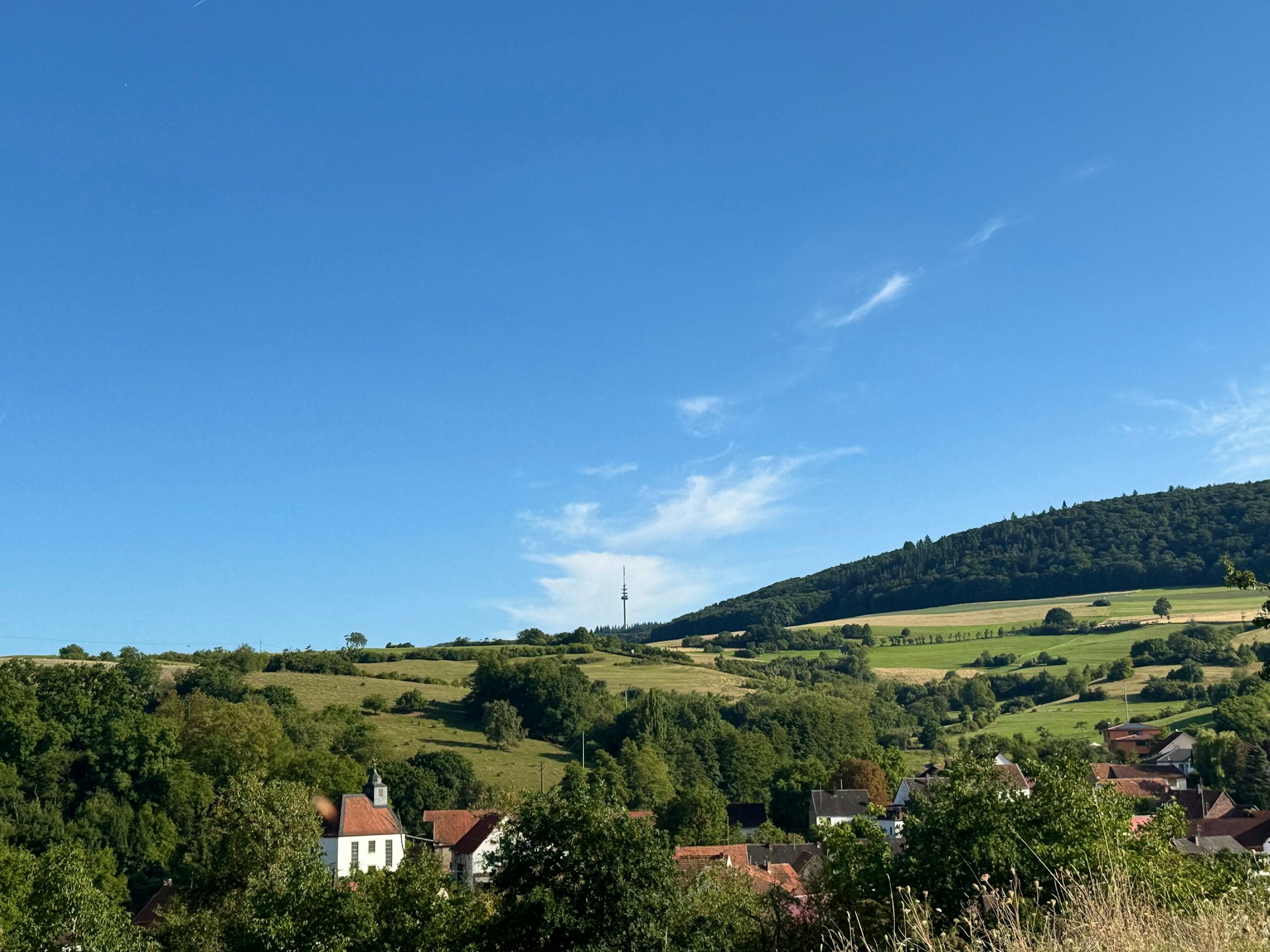 Village nestled in rolling green hills under blue sky
