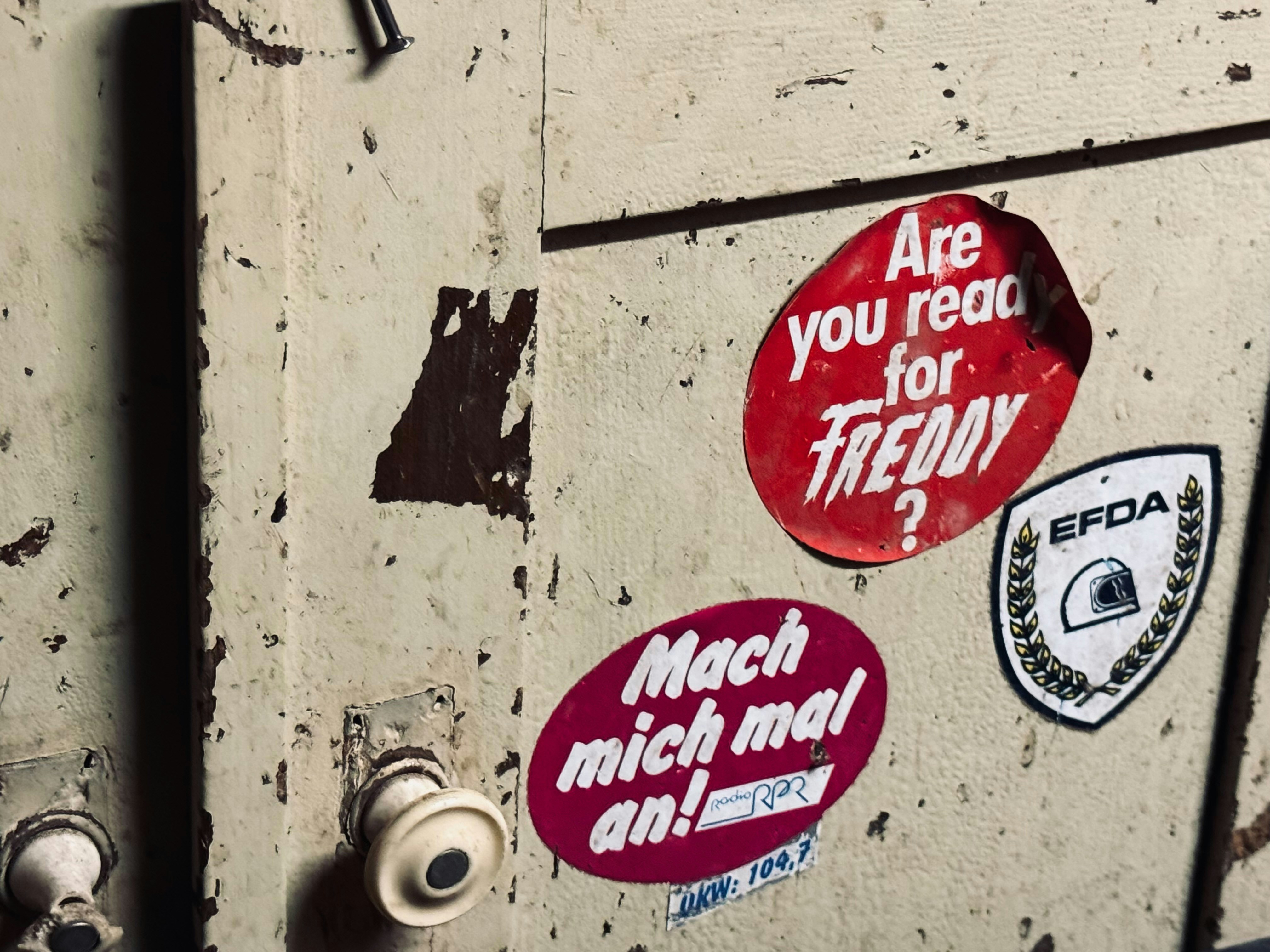 Alte Metalltür mit verschiedenen Aufklebern.