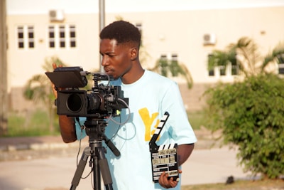 Young man operating a professional video camera on a tripod.