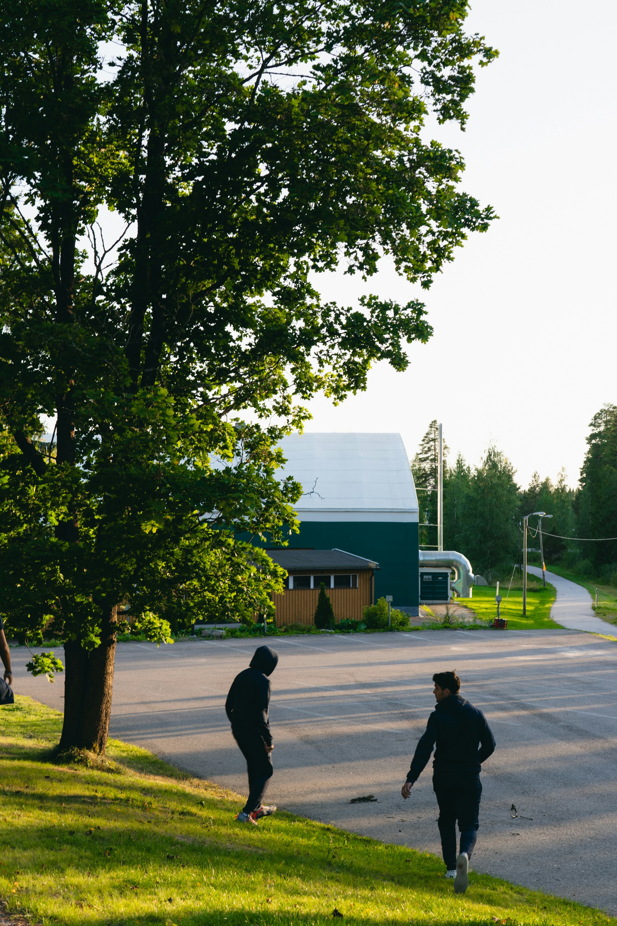 Two people walking on a sunny day near a building.