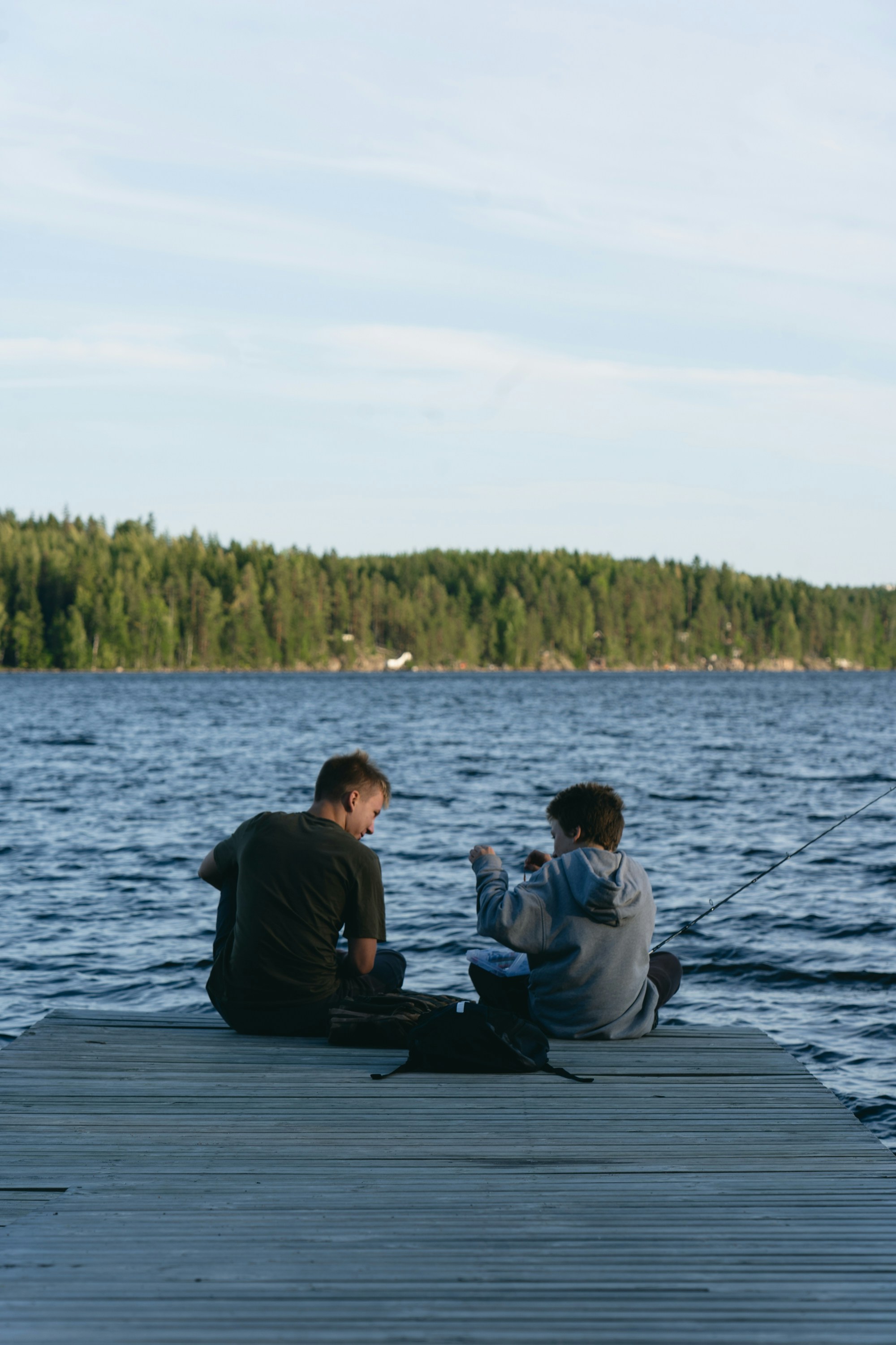 Two people fishing from a wooden dock.