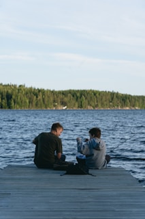 Two people fishing from a wooden dock.