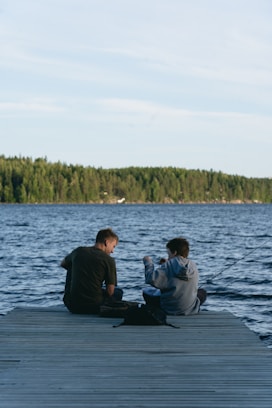 Two people fishing from a wooden dock.
