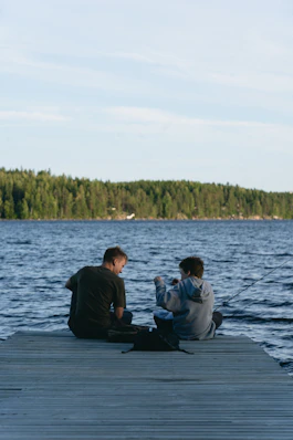 Two people fishing from a wooden dock.
