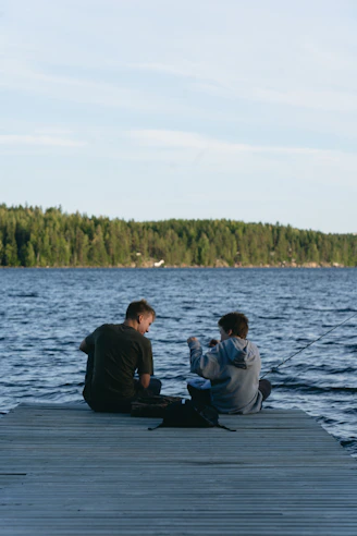 Two people fishing from a wooden dock.