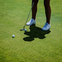 Golfer putting on a green with golf balls.