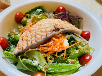 Grilled salmon fillet atop a fresh green salad.