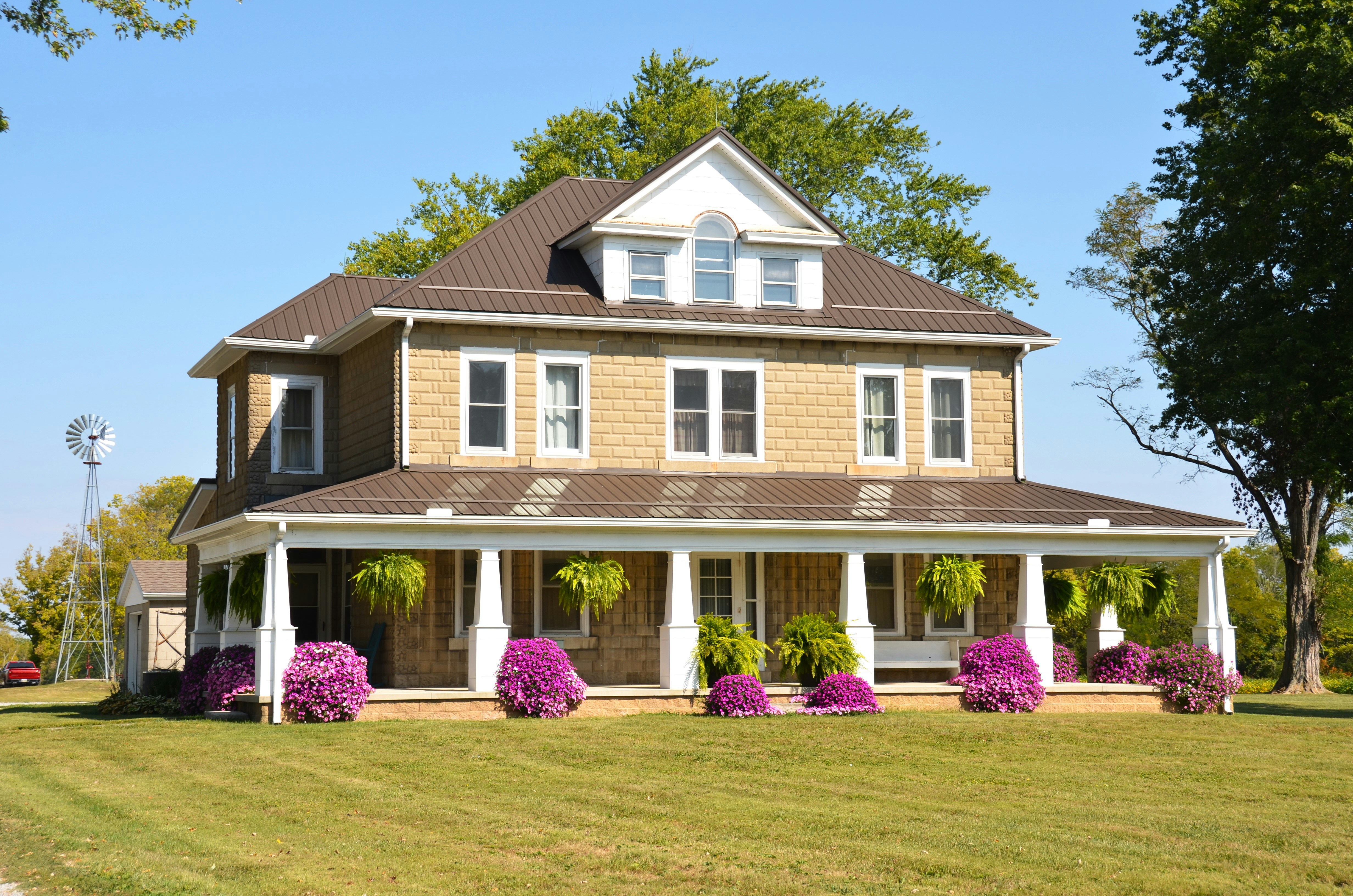 Tan two-story farmhouse with wrap-around porch