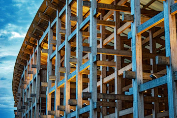 Wooden beams form a large abstract structure against sky