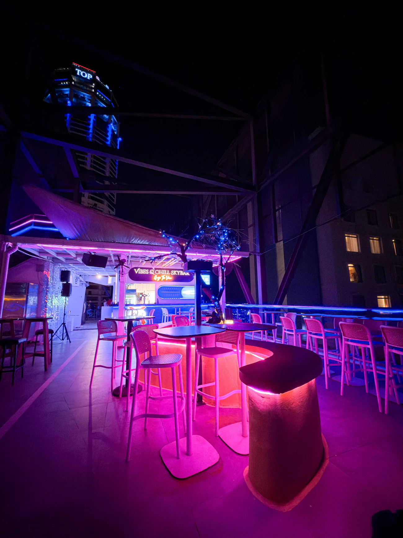 Toit-terrasse de nuit baigné de néons.