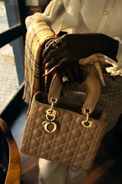 Woman holding a quilted beige handbag with charm