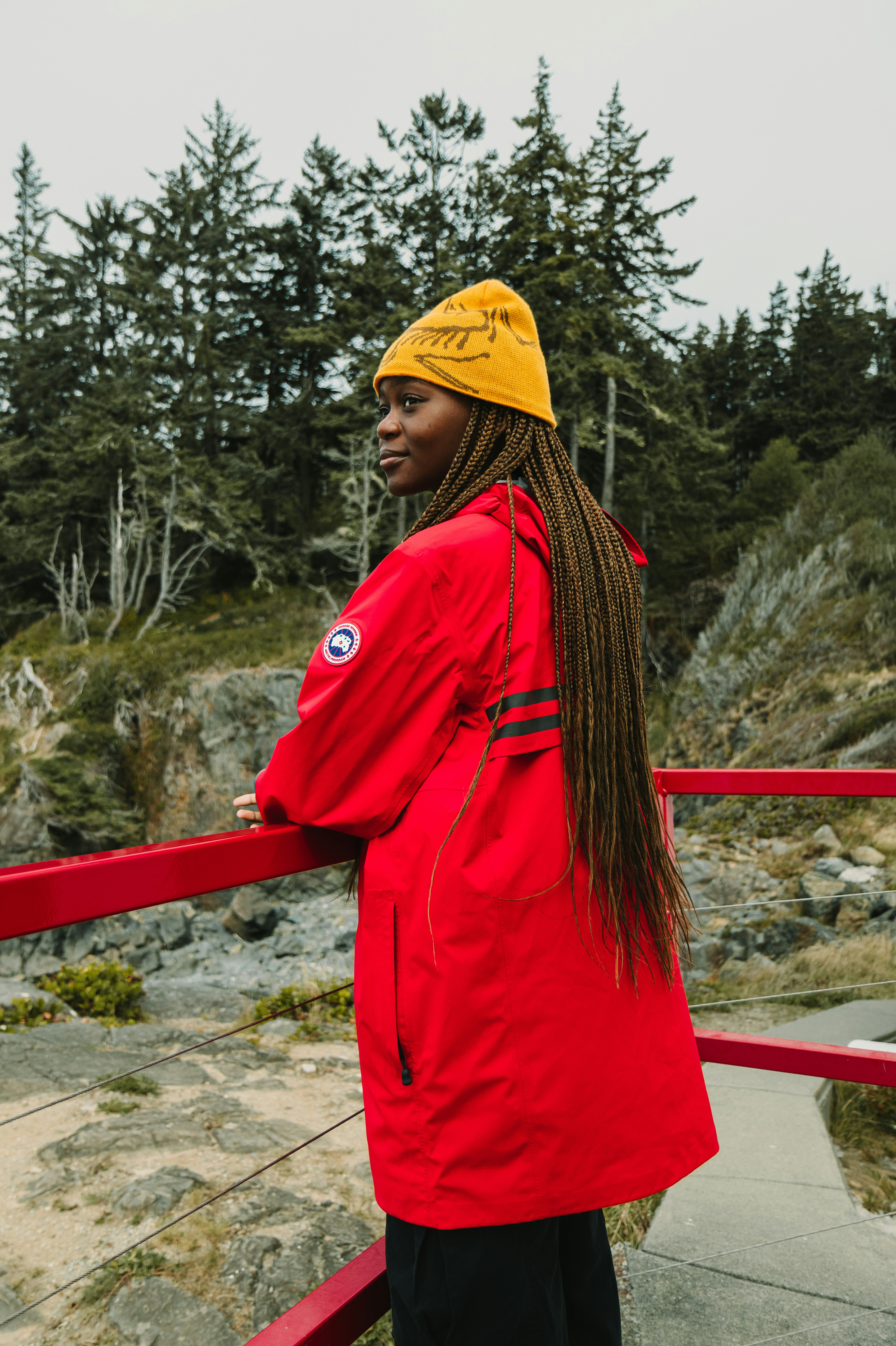 Woman in red jacket and yellow beanie by railing