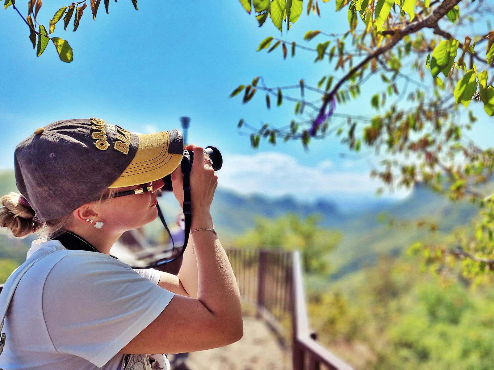 A creator with a camera framing a mountain landscape