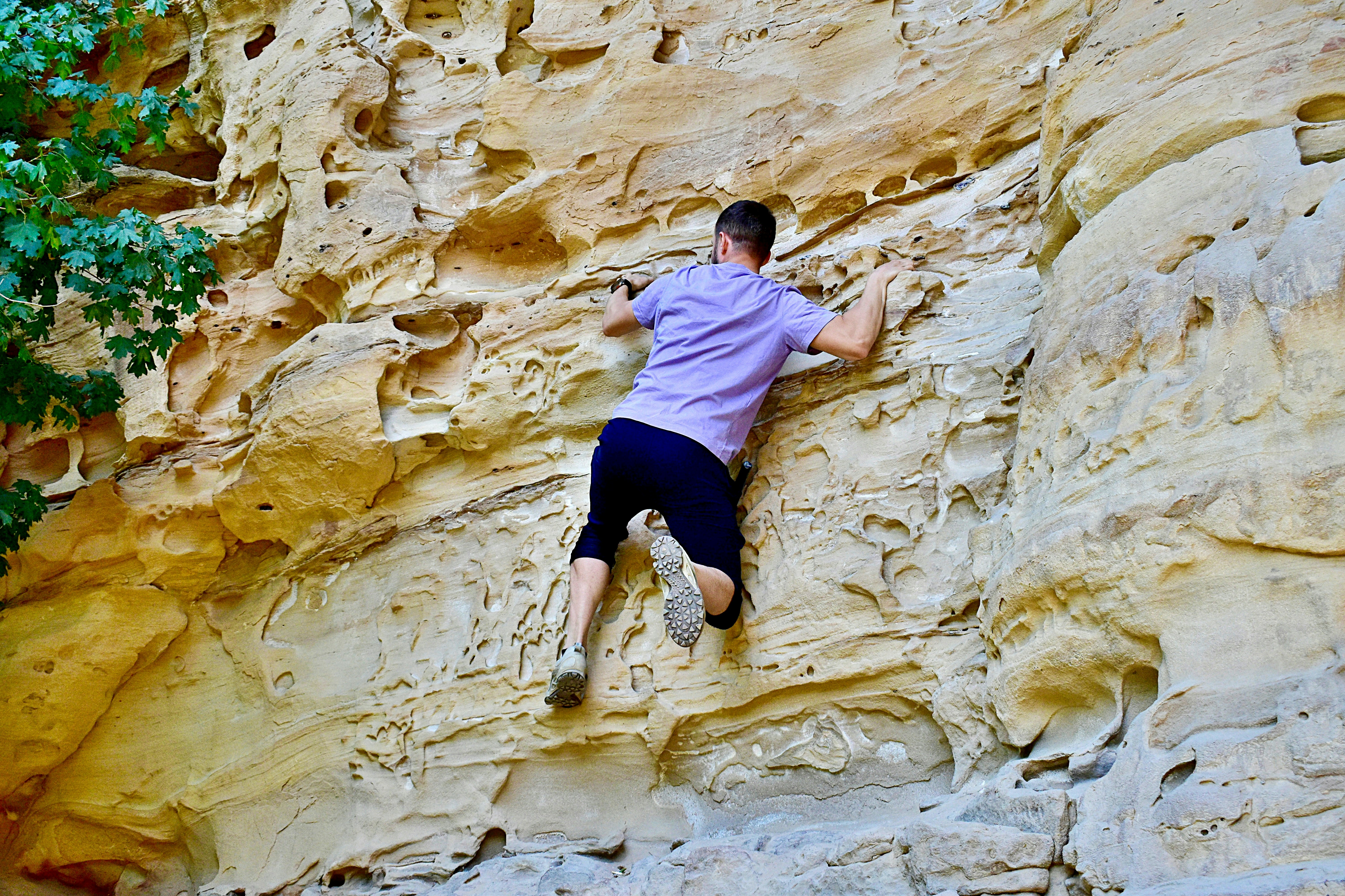 Man climbing a textured sandstone rock face