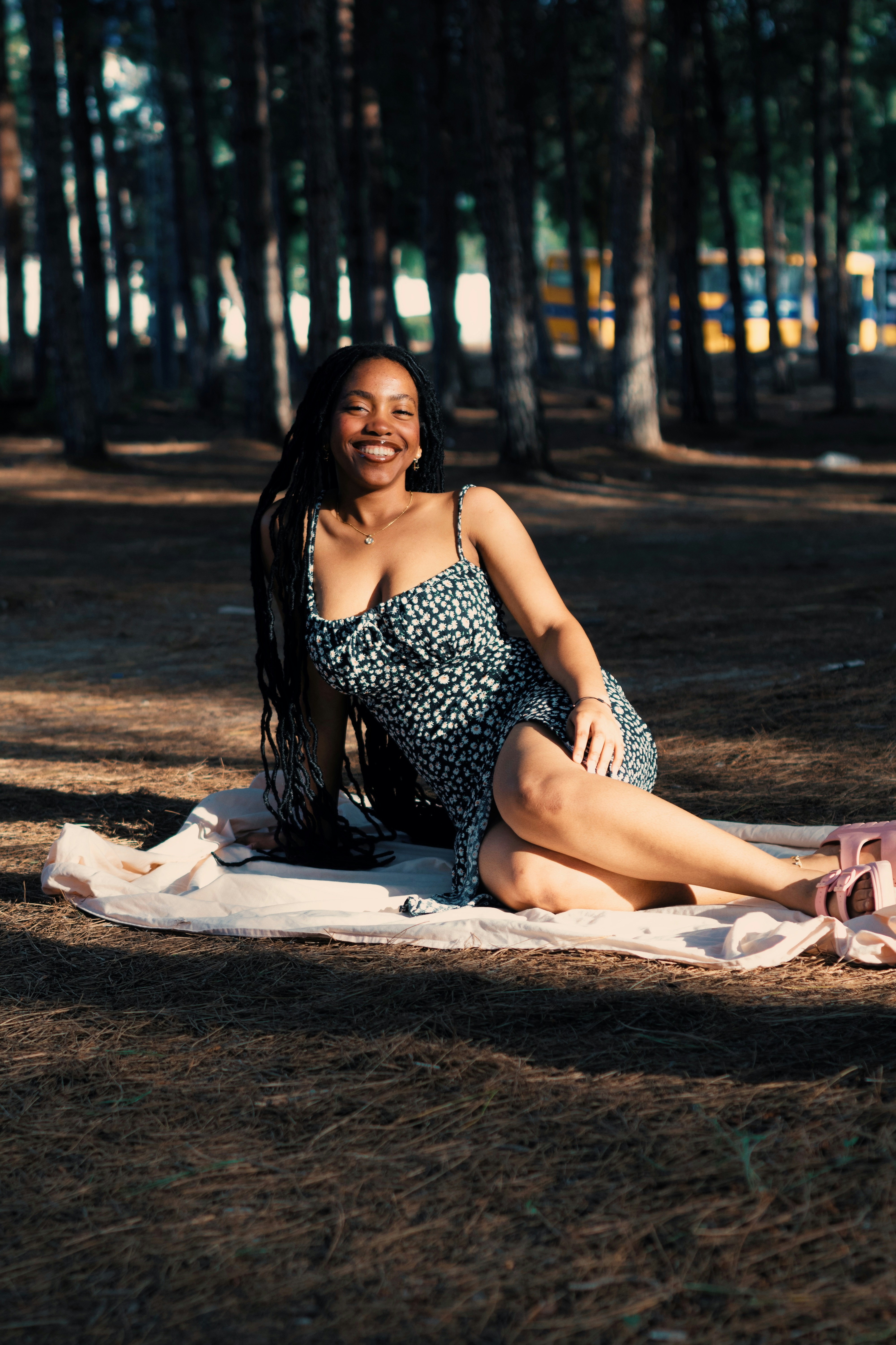 A smiling woman in a floral dress on a blanket