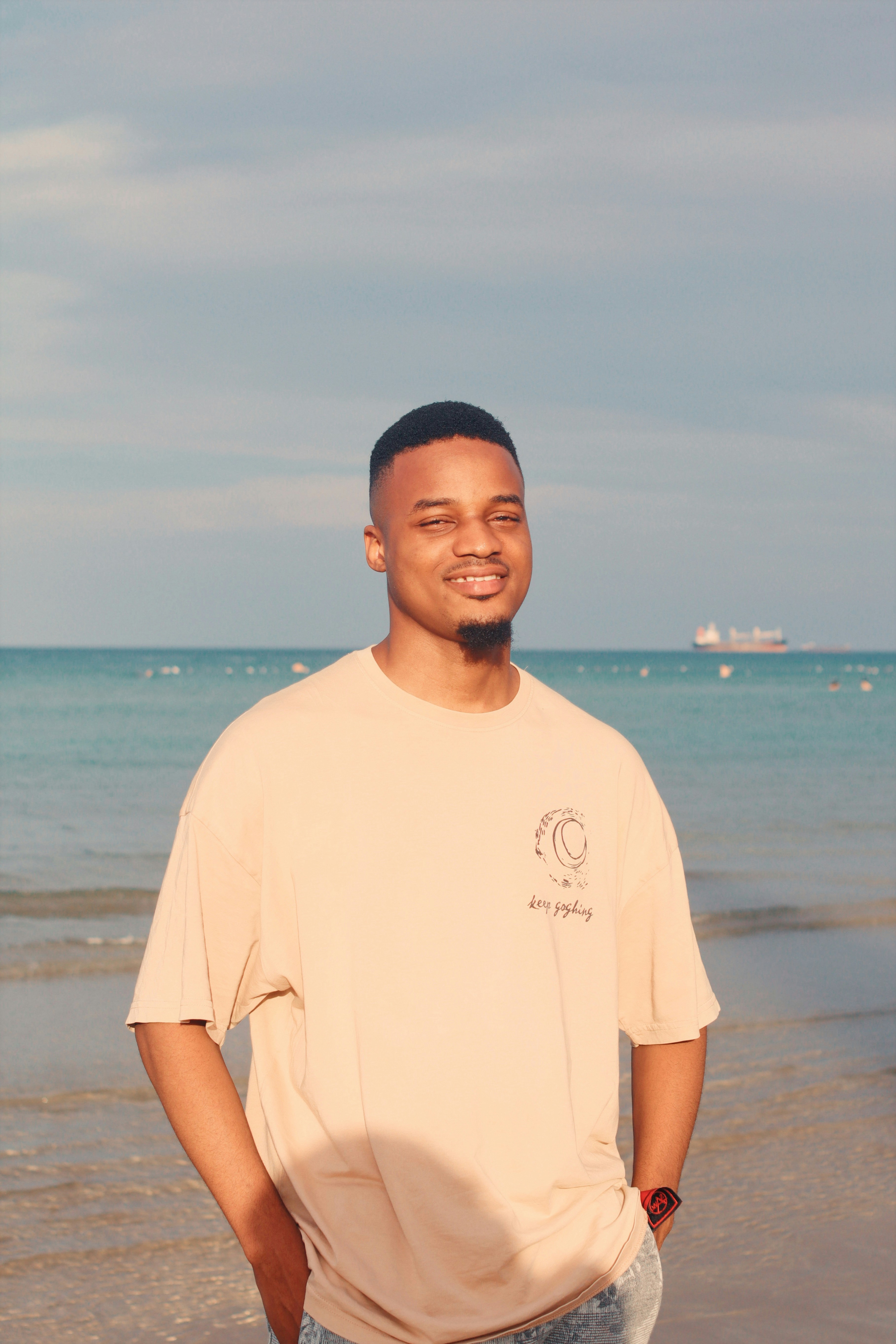 Young man smiling at the beach with ocean background.