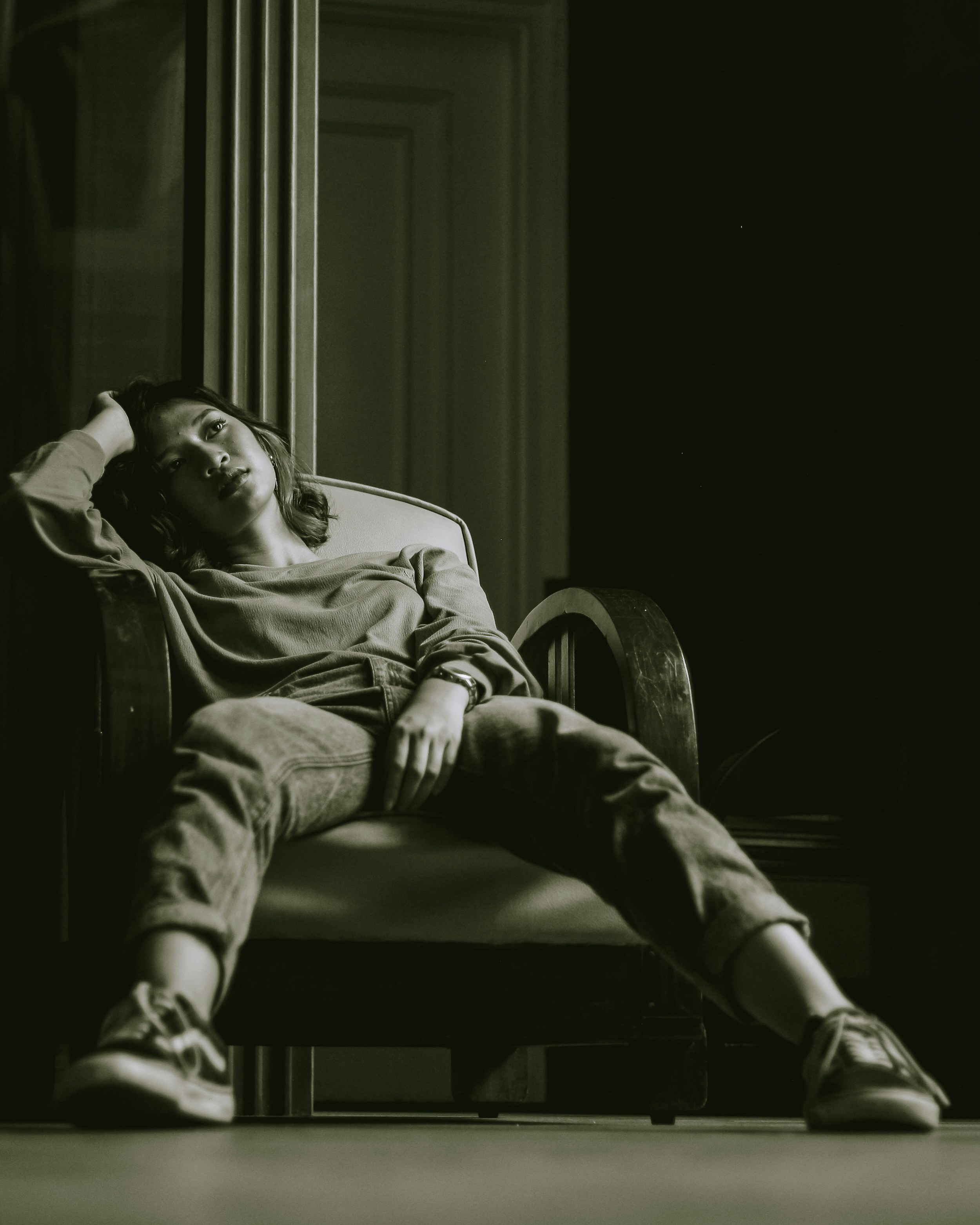 Woman sitting in chair with hand on head.