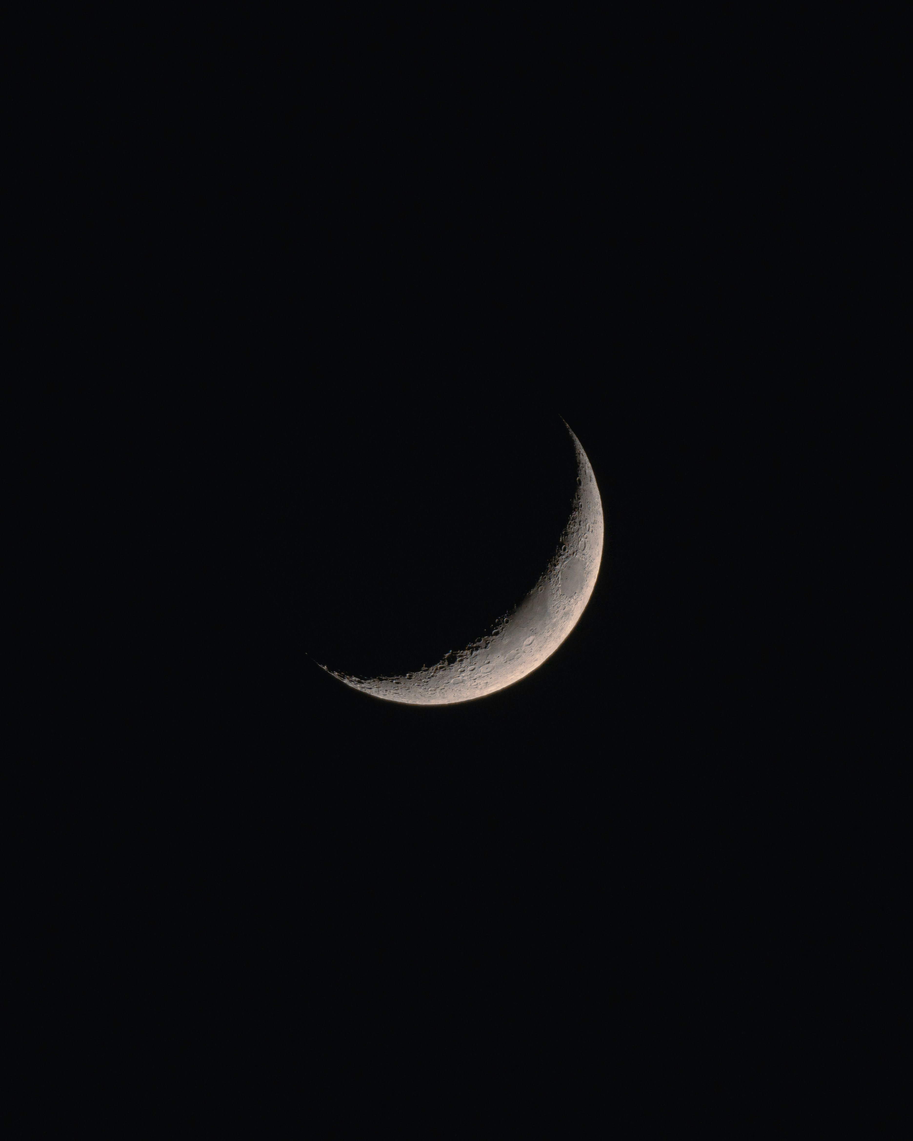 A crescent moon in a dark night sky.