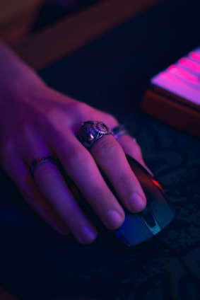 Hand wearing rings holding computer mouse