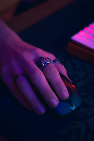 Hand wearing rings holding computer mouse
