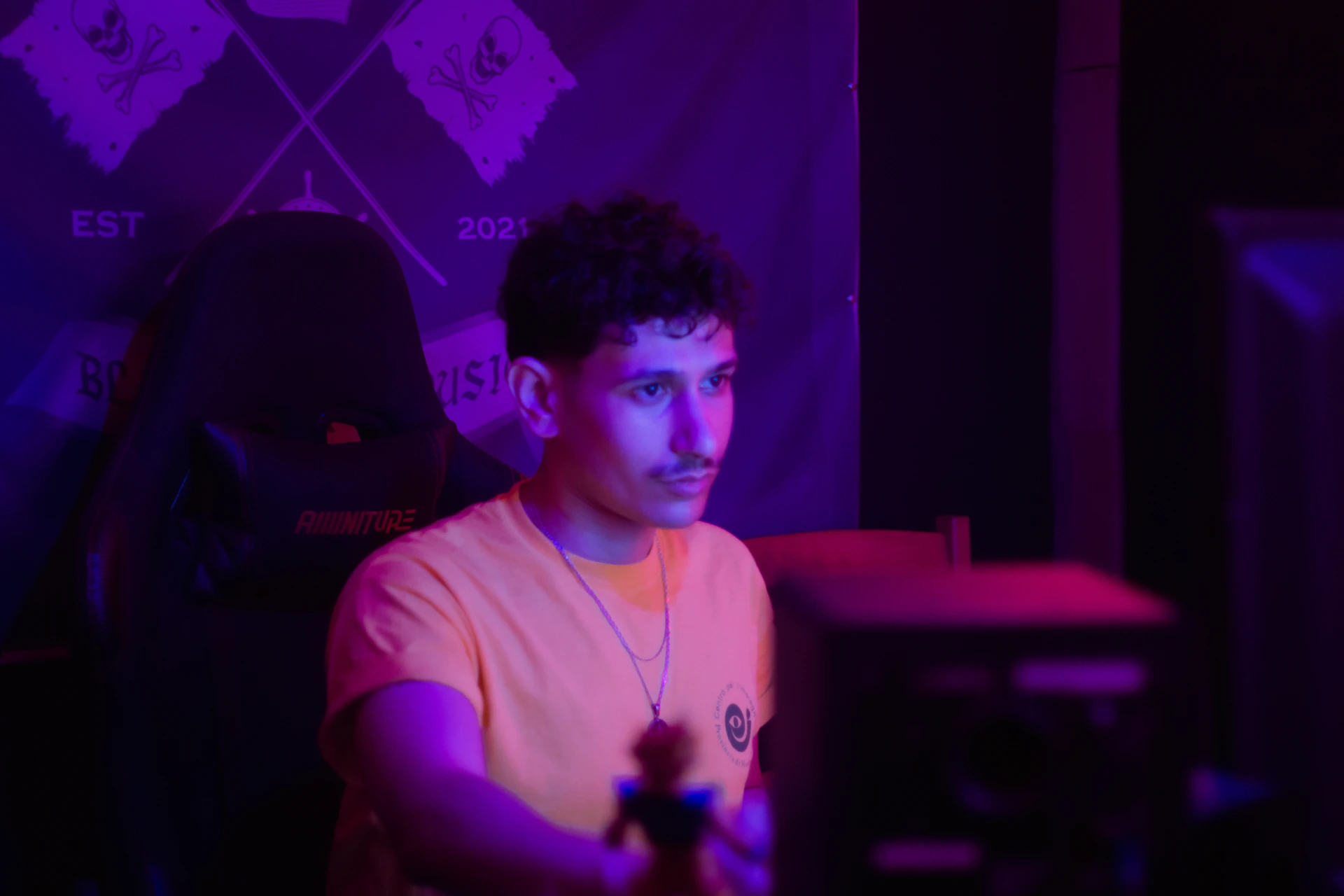 Young man in an orange shirt with purple lighting.