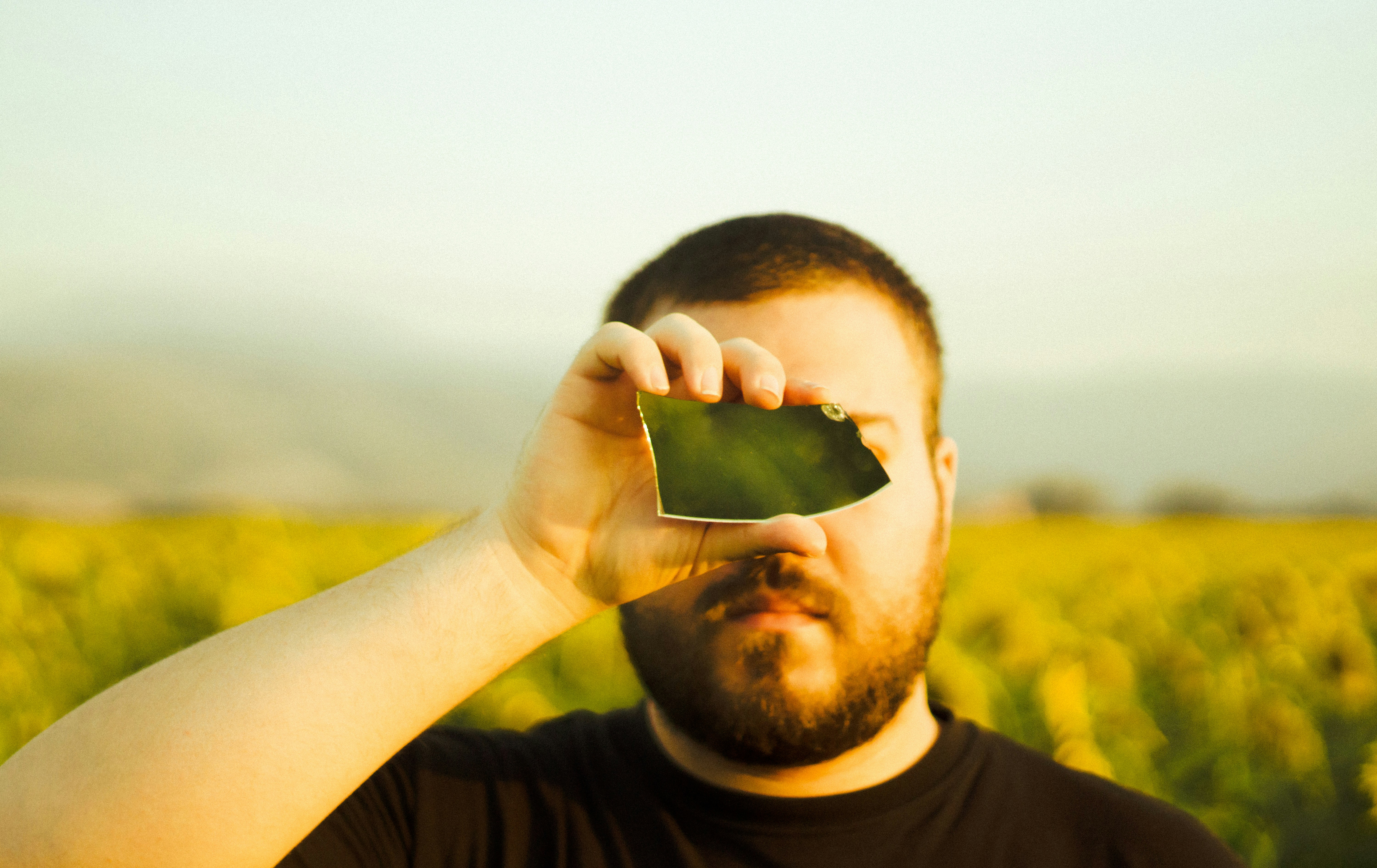Man holds broken mirror fragment to eye
