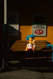 Cartoon character sits on bench with drink.