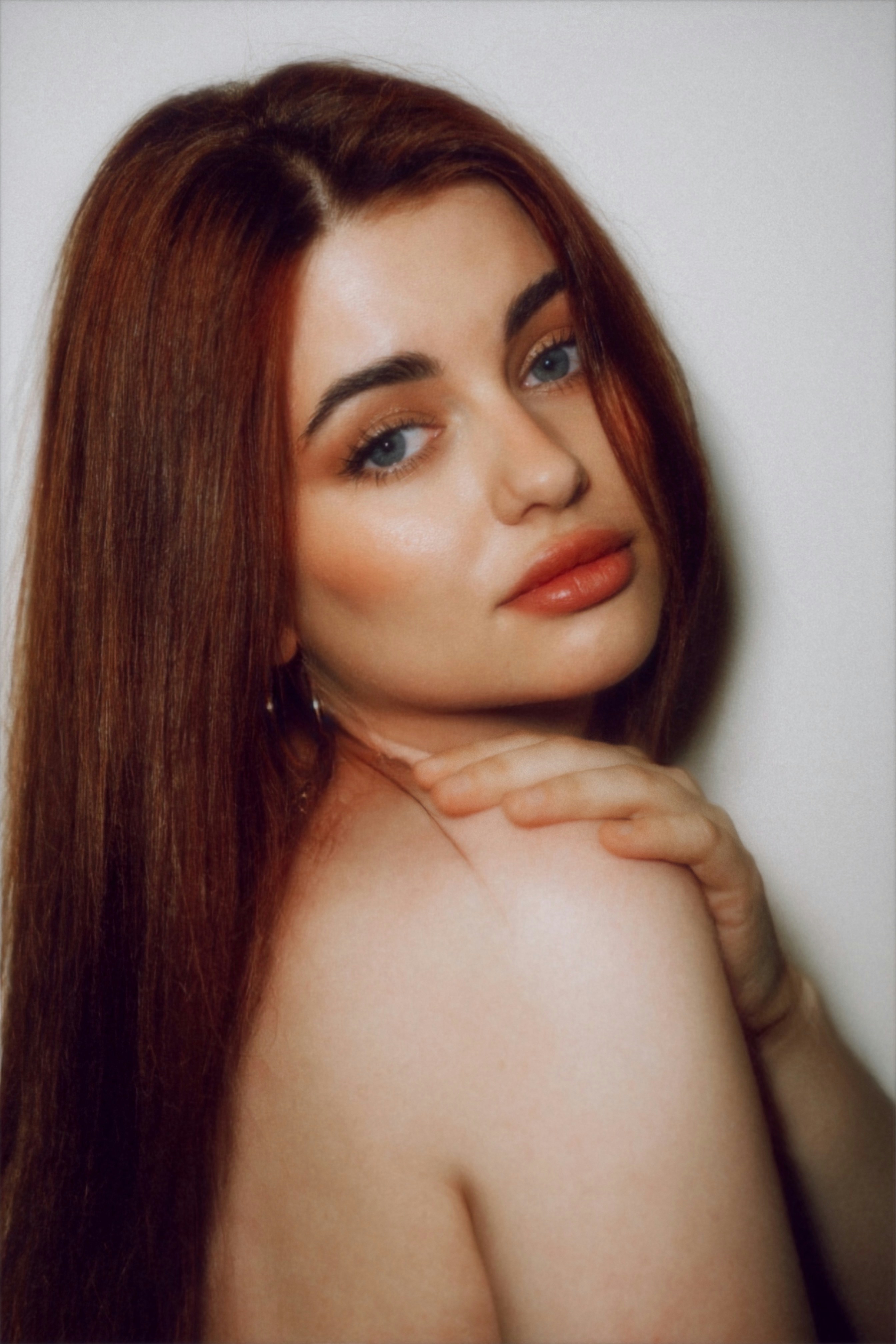 A young woman with red hair looks over her shoulder.